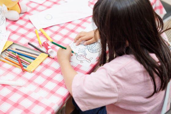 ミュートンの絵が描かれた紙にぬりえをする子どもの写真。