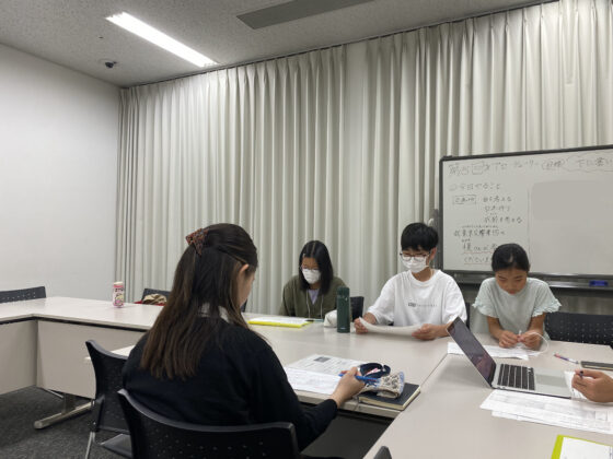 机を挟んで椅子に座り、東京交響楽団の方と打ち合わせををする企画班のメンバー。
