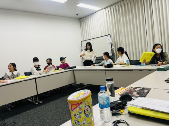 会議室の椅子に腰掛け、書類を準備したり談笑しながら会議のスタートを待つジュニア・プロデューサーたち。